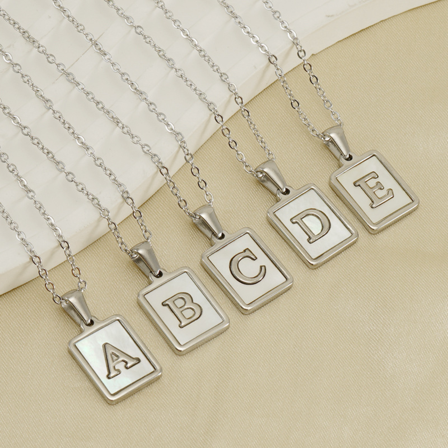 Silver initial letter charm necklaces with square pendants showing letters A, B, C, D and E