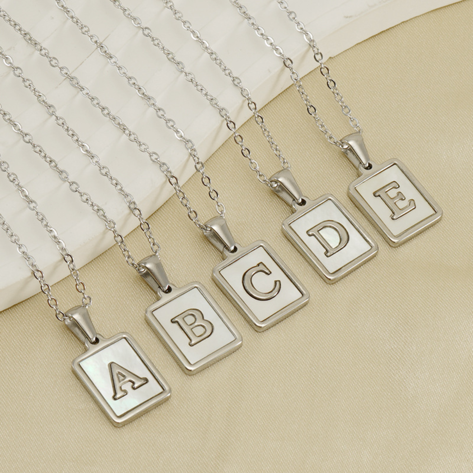 Silver initial letter charm necklaces with square pendants showing letters A, B, C, D and E